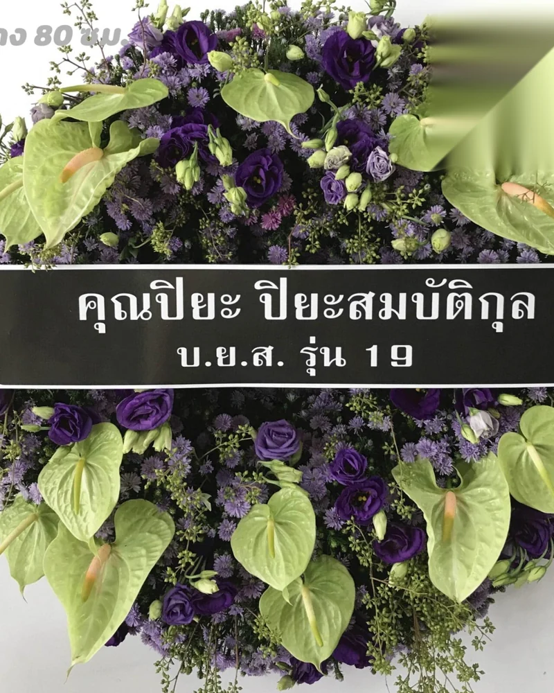 พวงหรีดดอกไม้สดจัดทรงกลมตั้งขาไม้หน้าศาลาบำเพ็ญกุศล