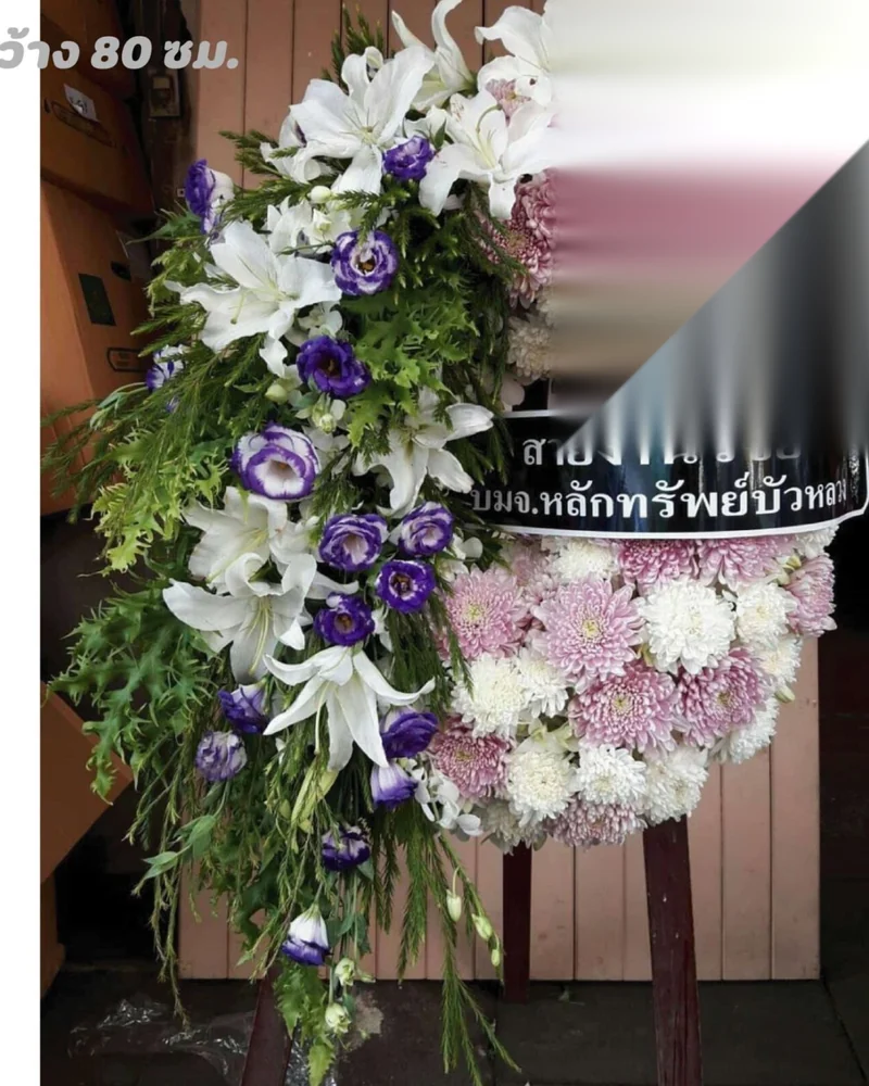 พวงหรีดดอกไม้สดโทนม่วงชมพูตั้งอยู่หน้าศาลา