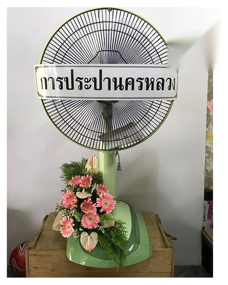 พวงหรีดพัดลมพร้อมป้ายข้อความไว้อาลัยที่ตั้งอยู่หน้าศาลาวัด