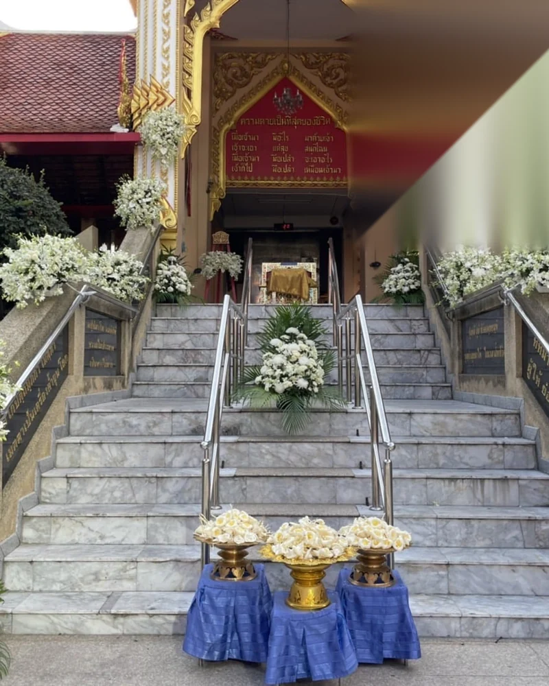 บันไดหินอ่อนขึ้นศาลาสวดมีป้ายข้อความธรรมะสีแดงทองและพวงหรีดดอกไม้ขาวสองข้าง