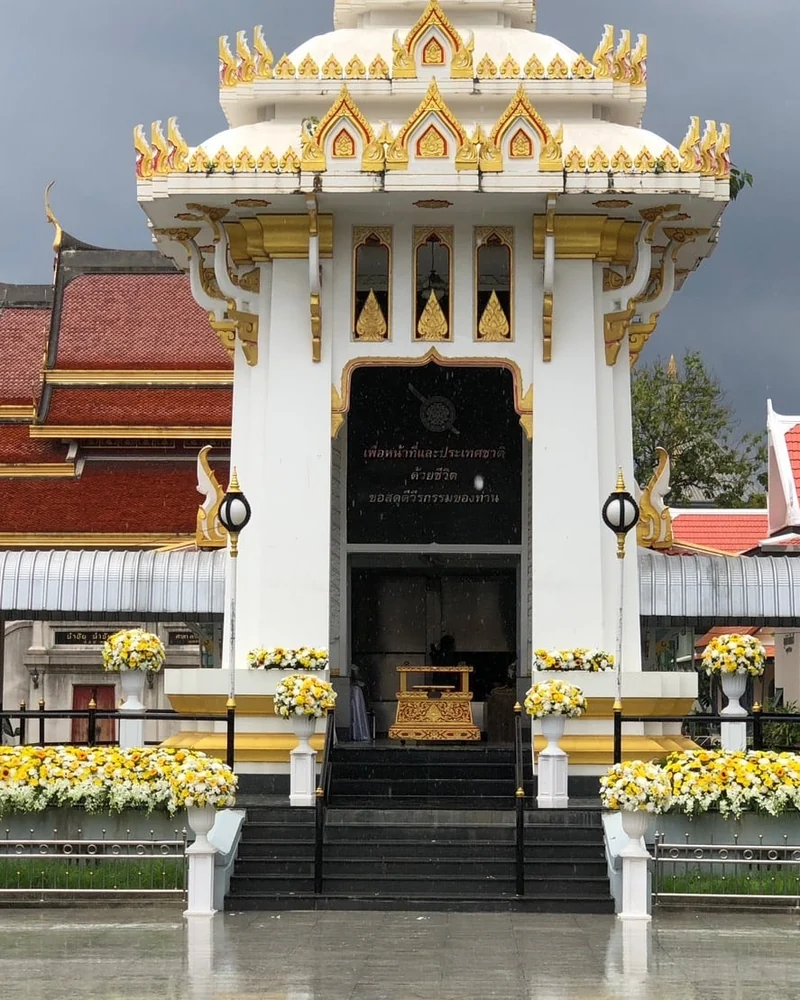 ศาลาทรงไทยหลังคาทองประดับดอกไม้สีเหลืองขาวในวันฝนตกท้องฟ้าครึ้ม