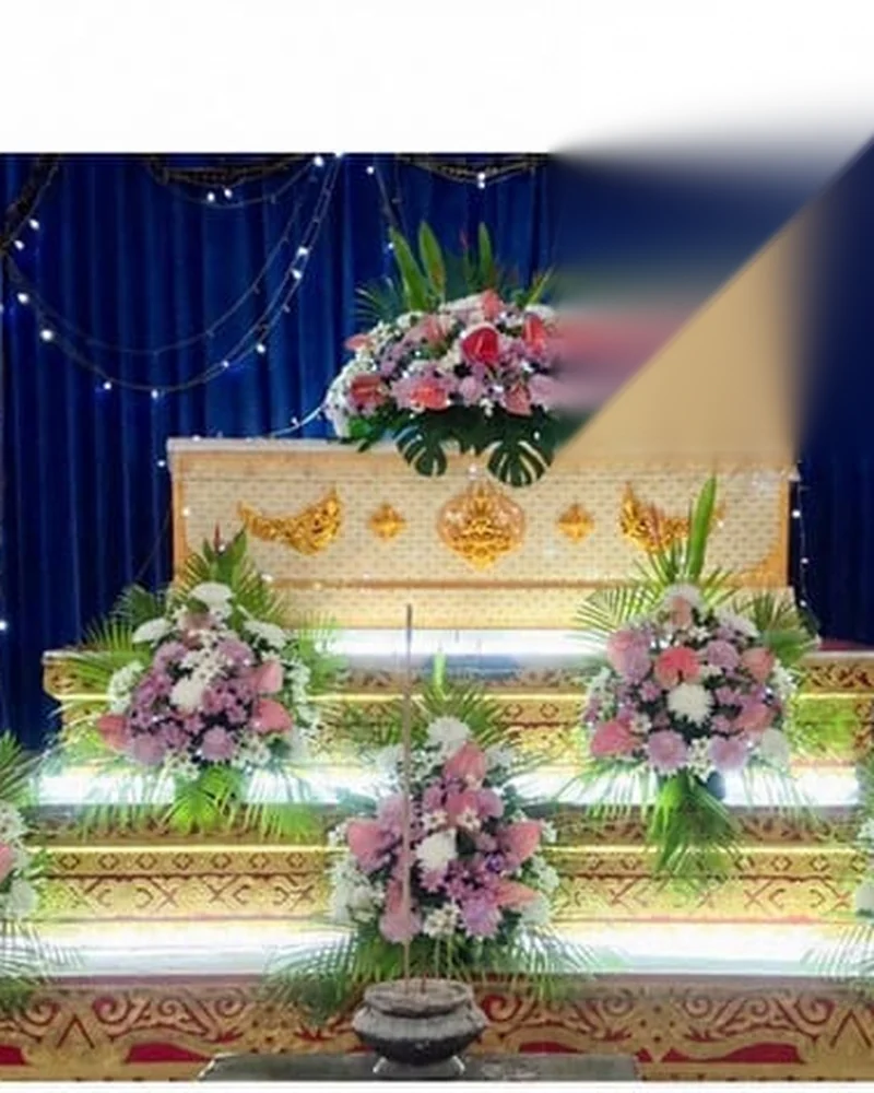 โลงศพสีทองประดับดอกไม้หลายชั้นวางบนแท่นภายในศาลา